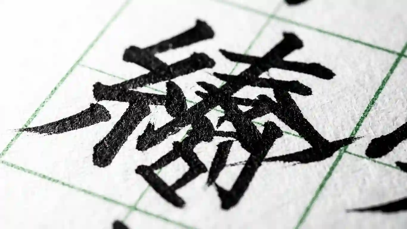Primer plano macro de una pluma estilográfica de caligrafía goteando tinta negra densa sobre un papel rugoso con un patrón de cuadrícula.