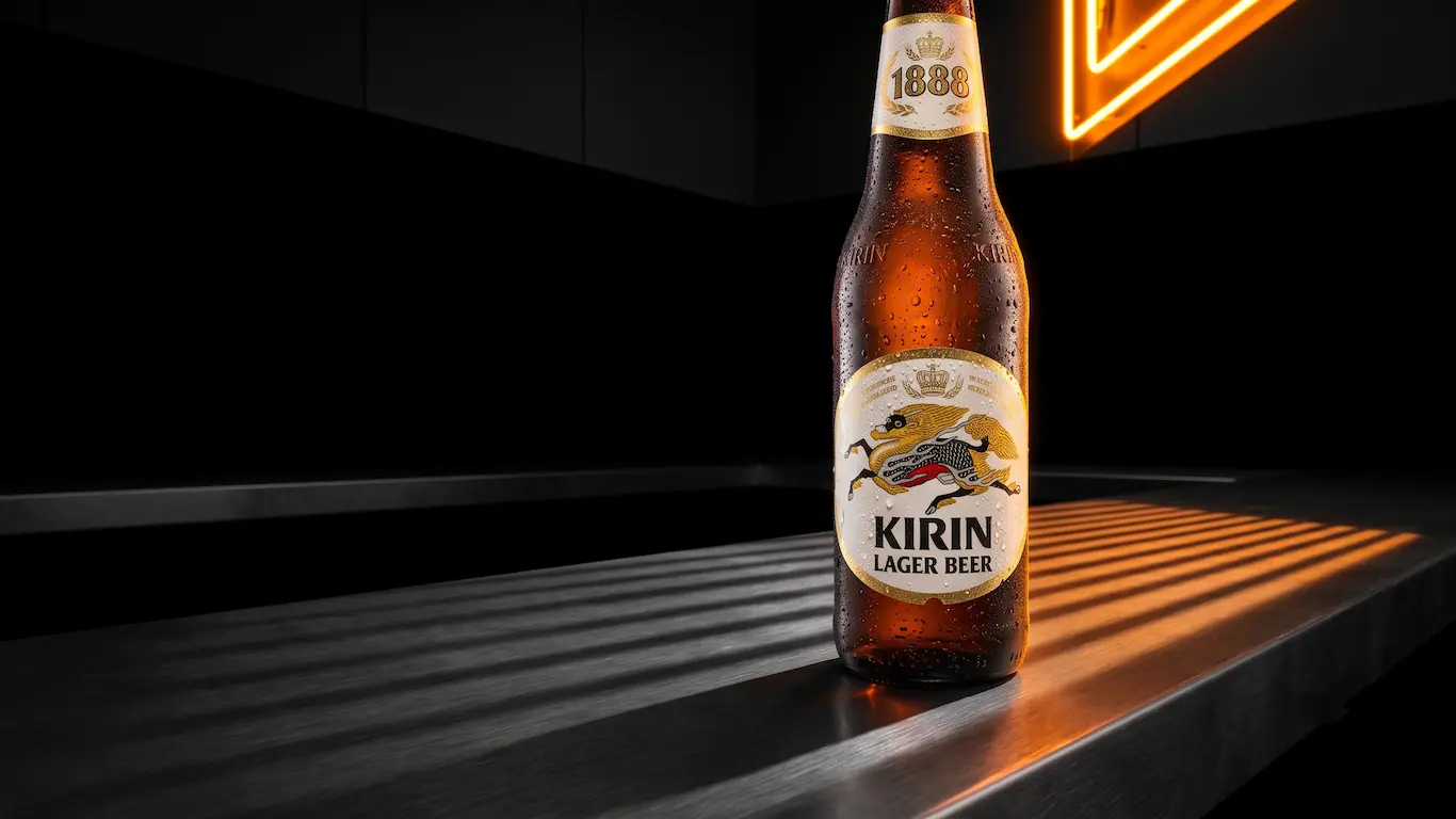 Vista de ángulo ancho de una botella de cerveza Kirin fría sobre una barra metálica oscura, iluminada por un neón naranja.